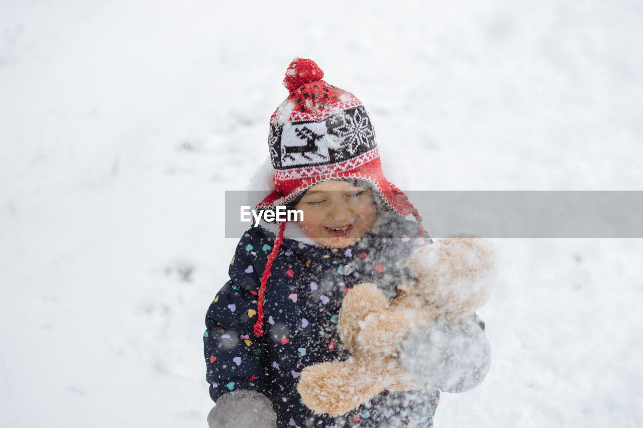 Cute little girl having fun playing outdoor during snowfall. 