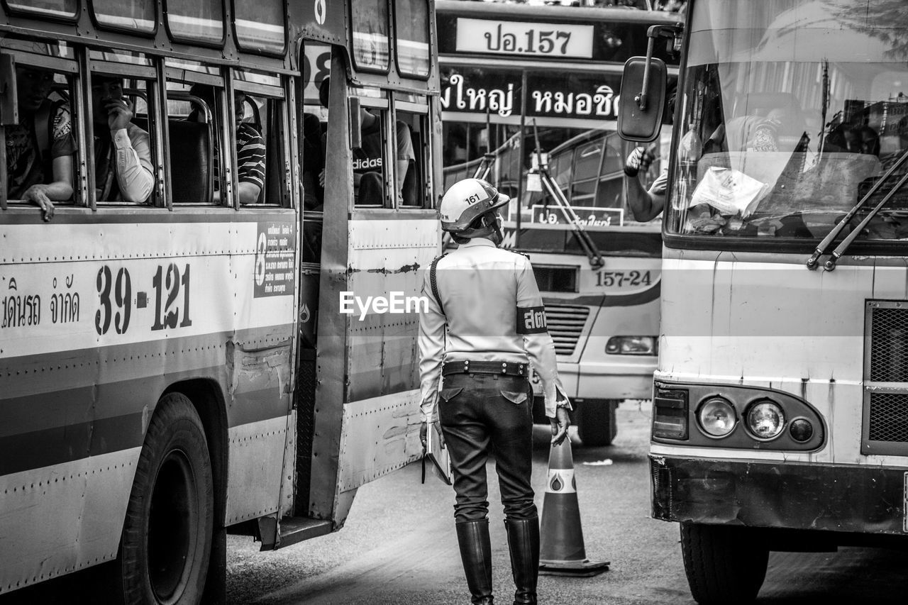 Traffic cop standing on street with buses in traffic jam