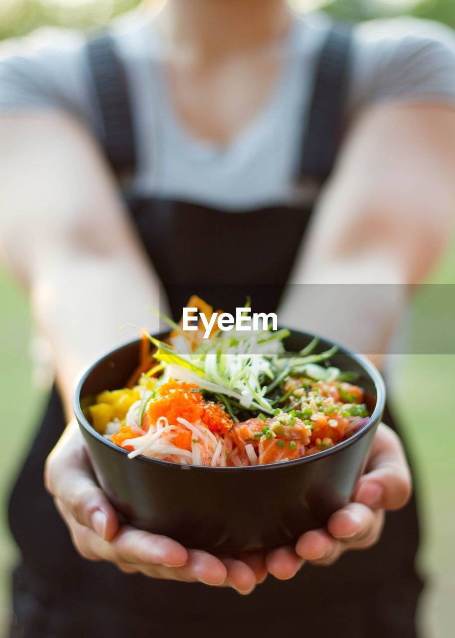 Midsection of woman holding poke bowl