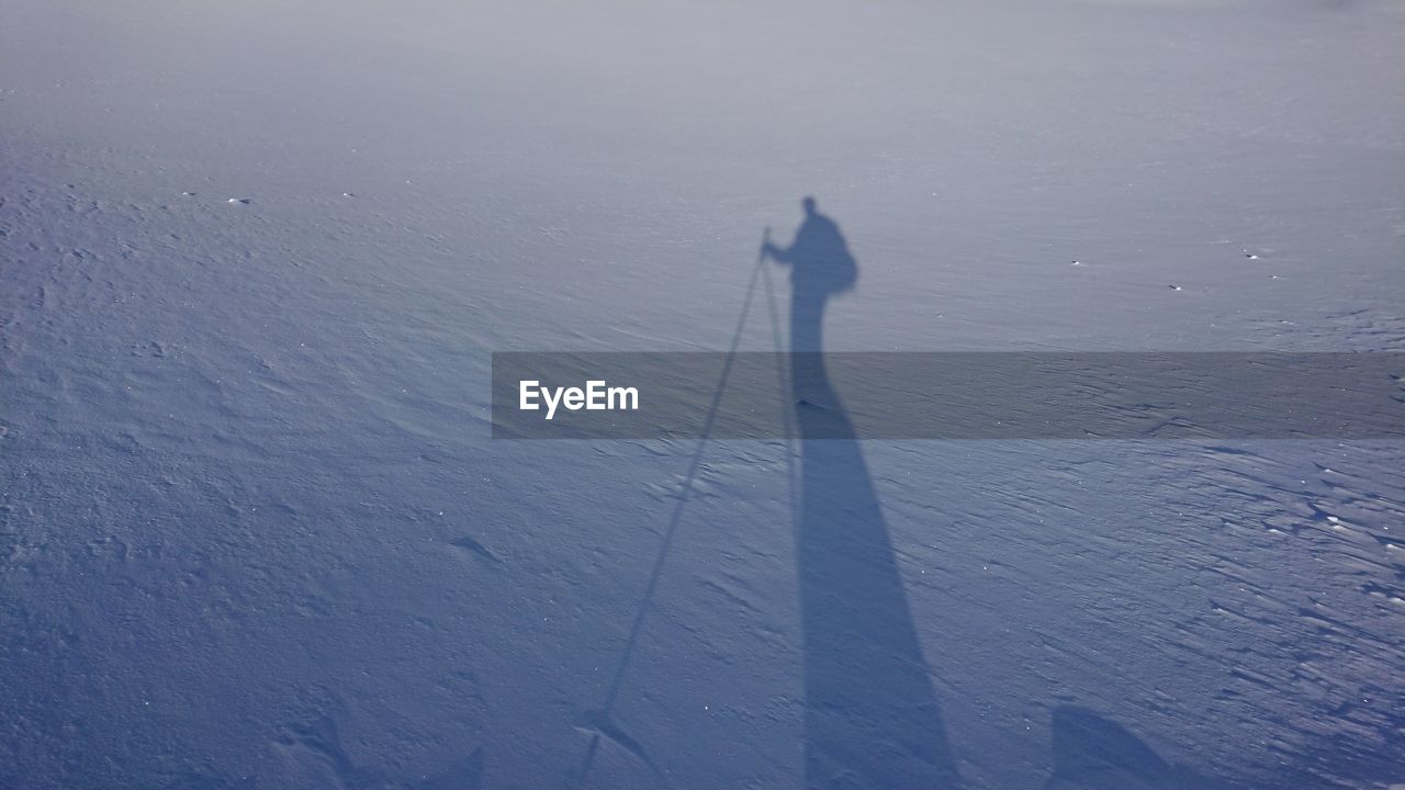 SHADOW OF PERSON STANDING ON SNOW LAND