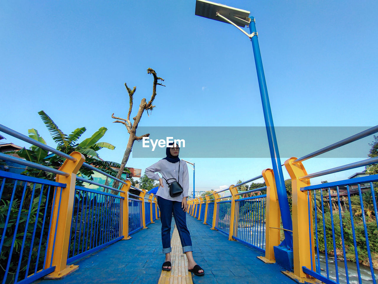 Man standing on railing against blue sky