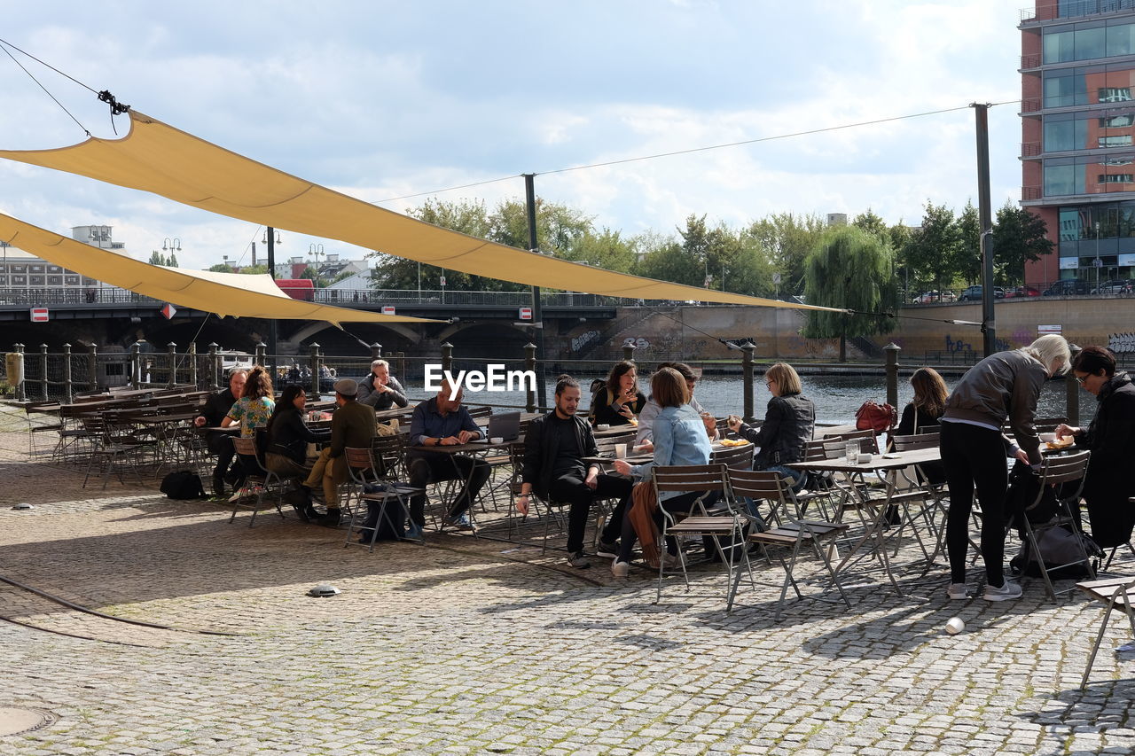 PEOPLE SITTING IN CITY AGAINST SKY