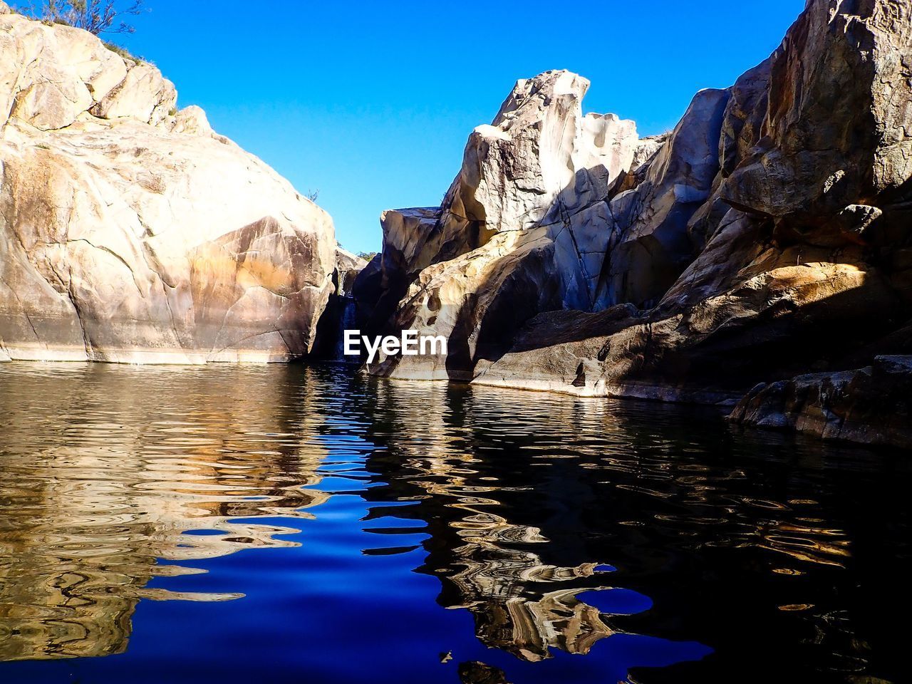 REFLECTION OF ROCKS IN LAKE AGAINST SKY