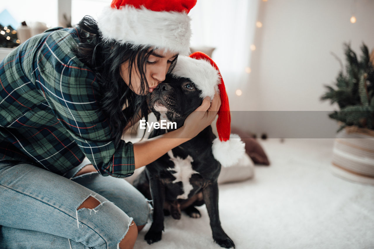 Smiling woman sitting on bed with dog at home