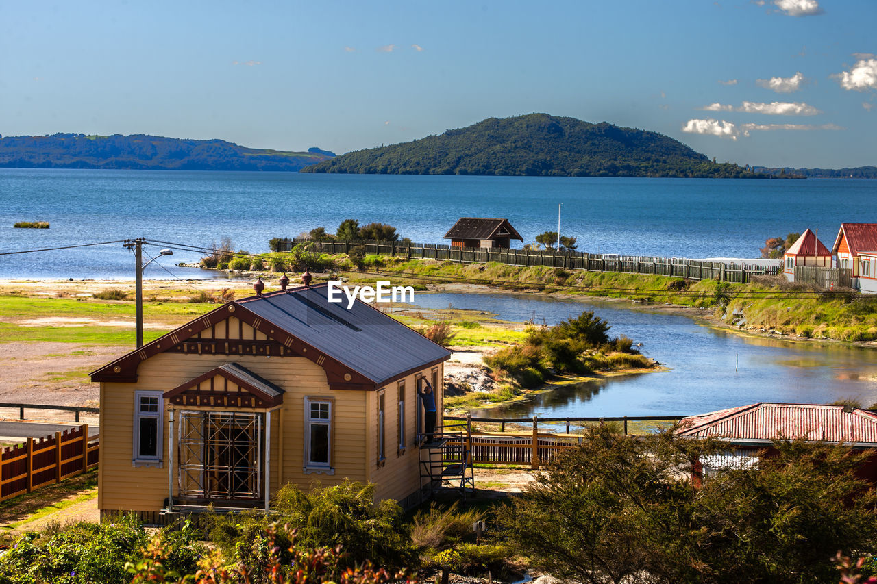 Houses by lake against sky