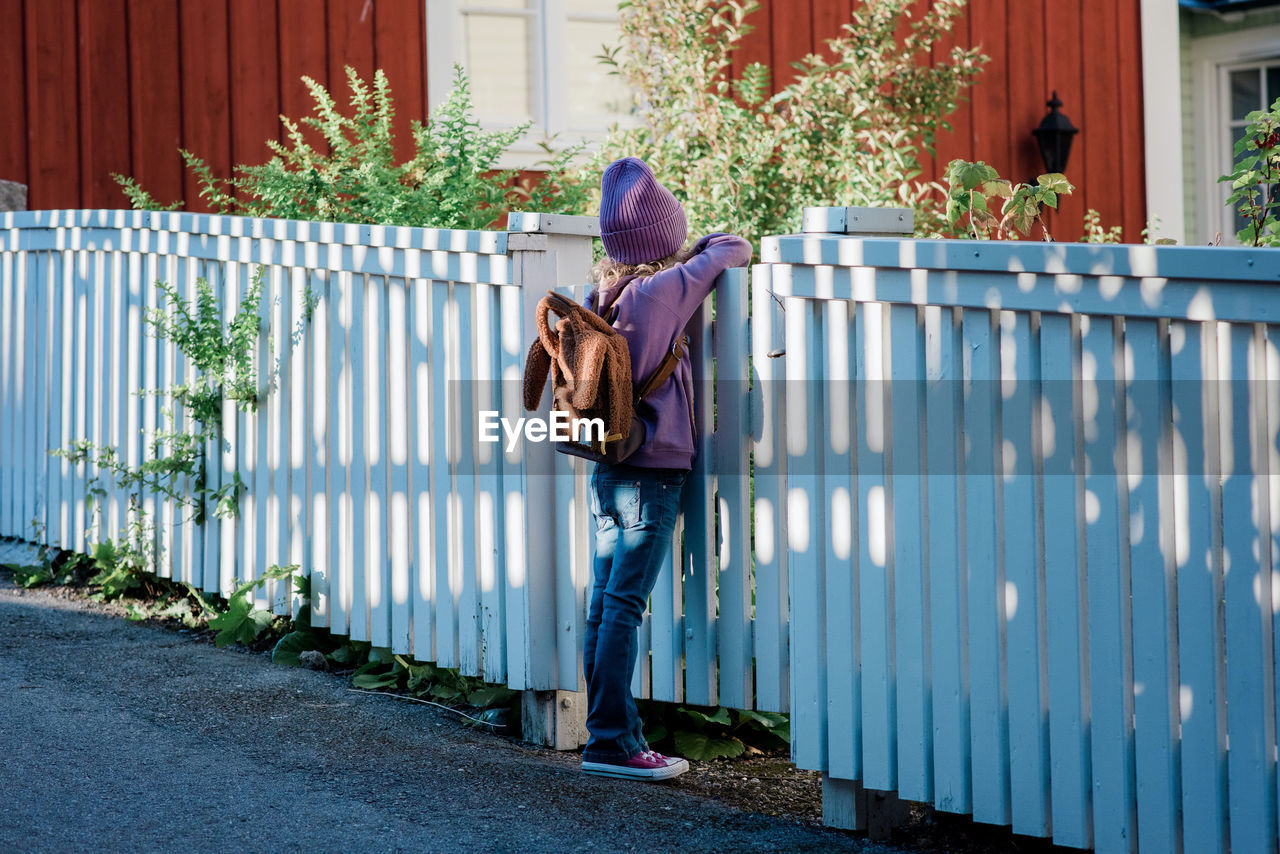 Young girl leaning on a fence looking into the distance waiting