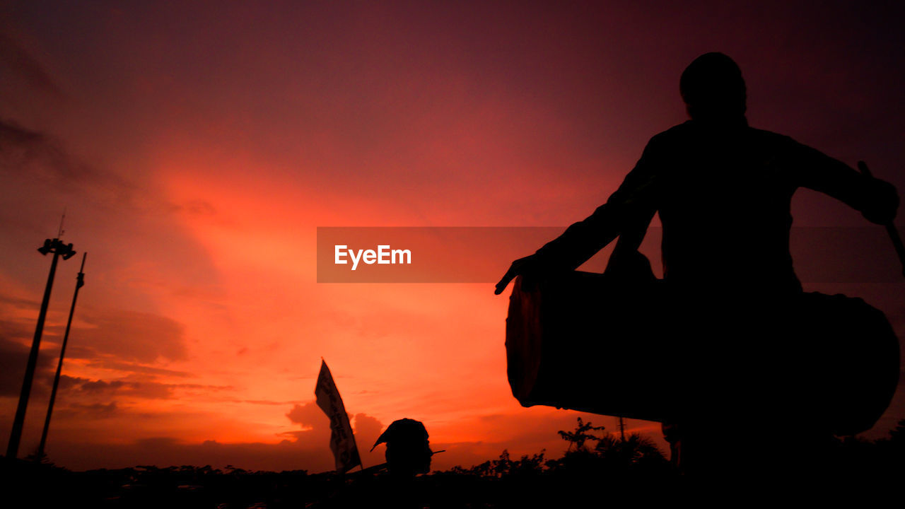 SILHOUETTE MAN STATUE AGAINST SUNSET SKY