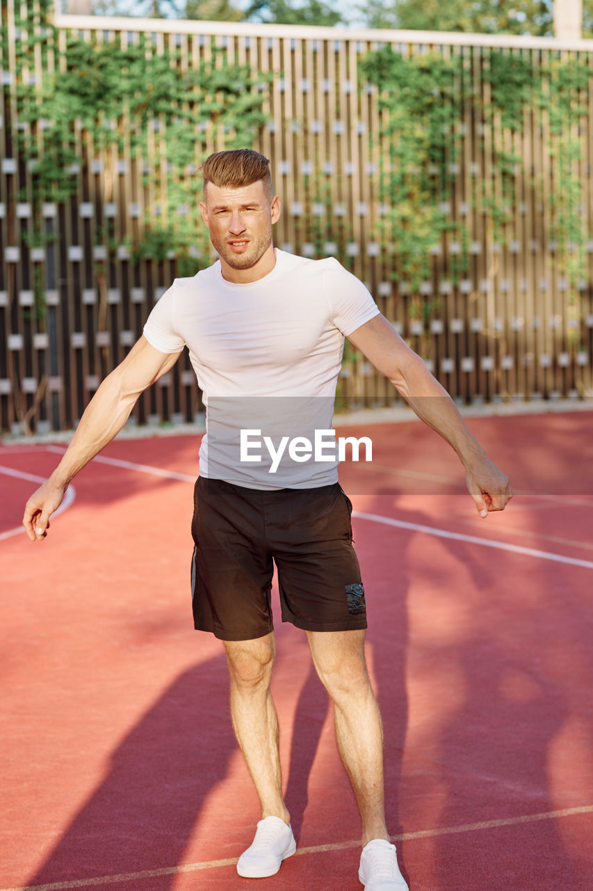 full length of young woman exercising on court