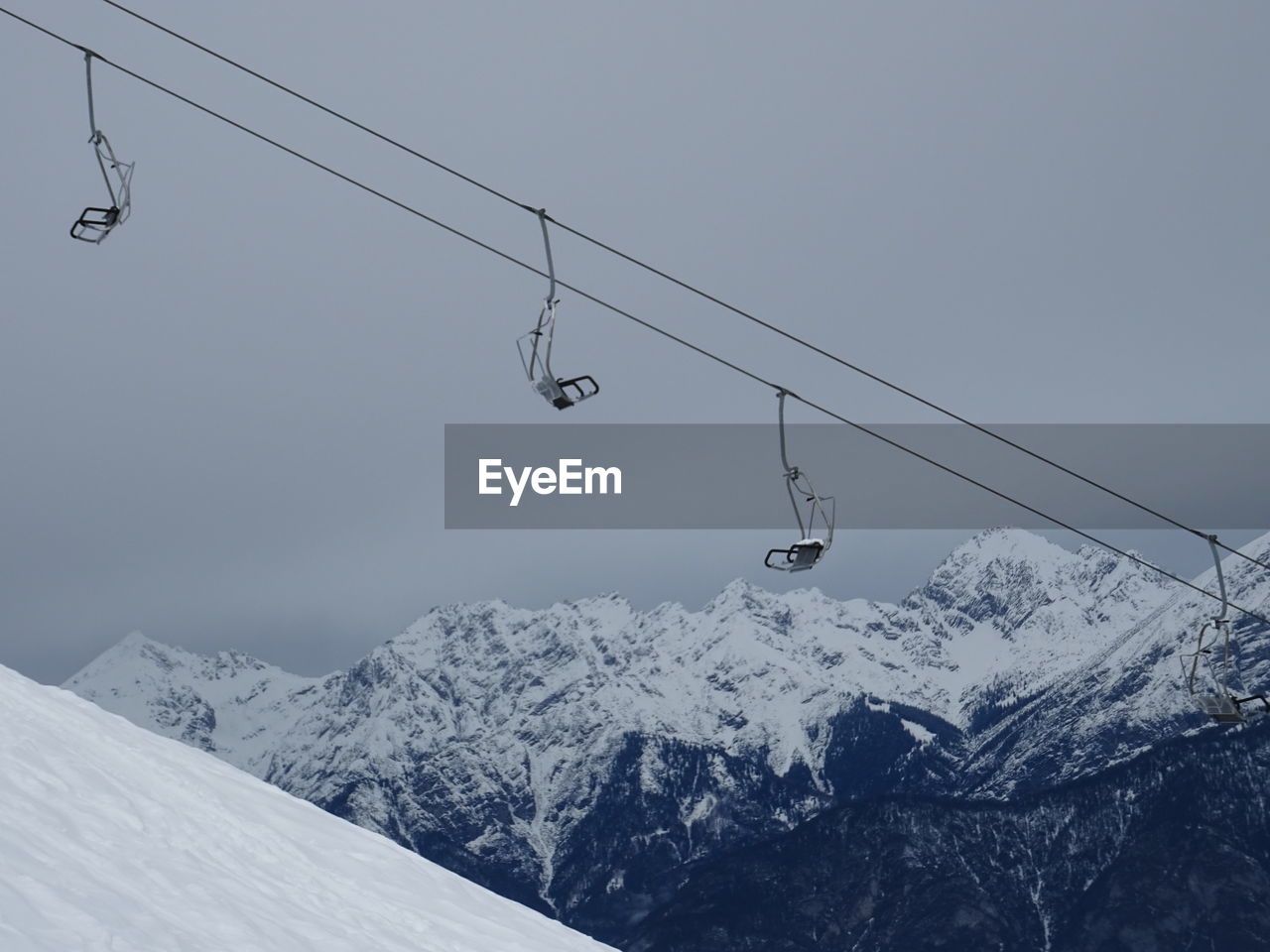 OVERHEAD CABLE CAR OVER SNOW COVERED MOUNTAINS