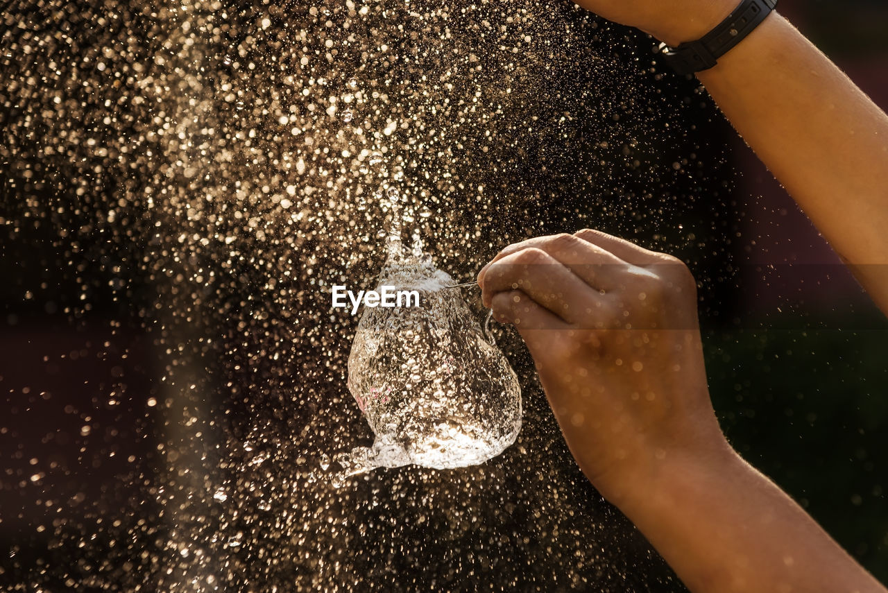 Cropped hands bursting water balloon