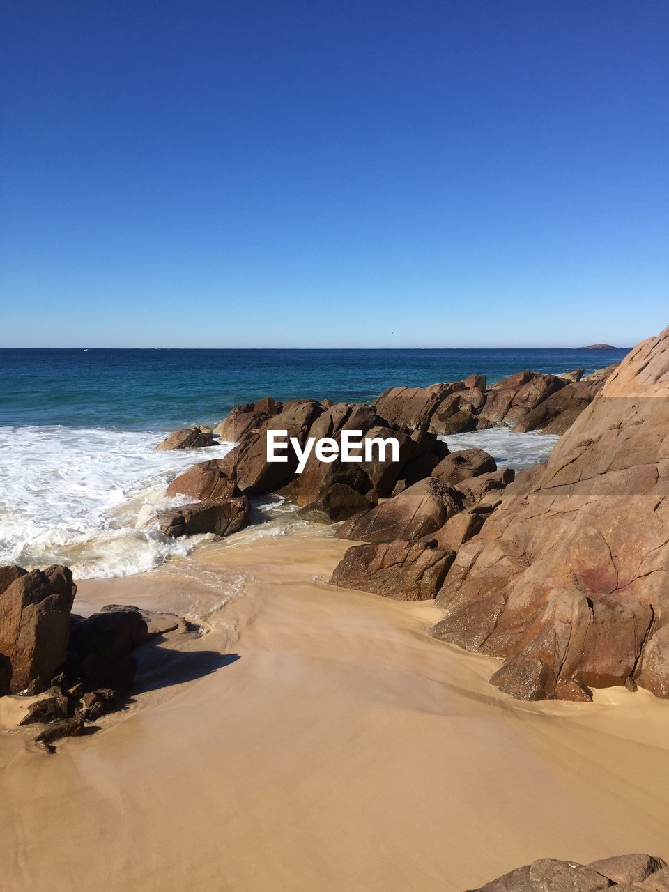 Scenic view of beach against clear blue sky