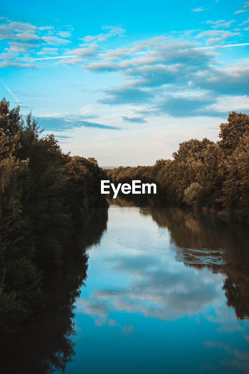 Scenic view of calm lake amidst trees against sky during sunset