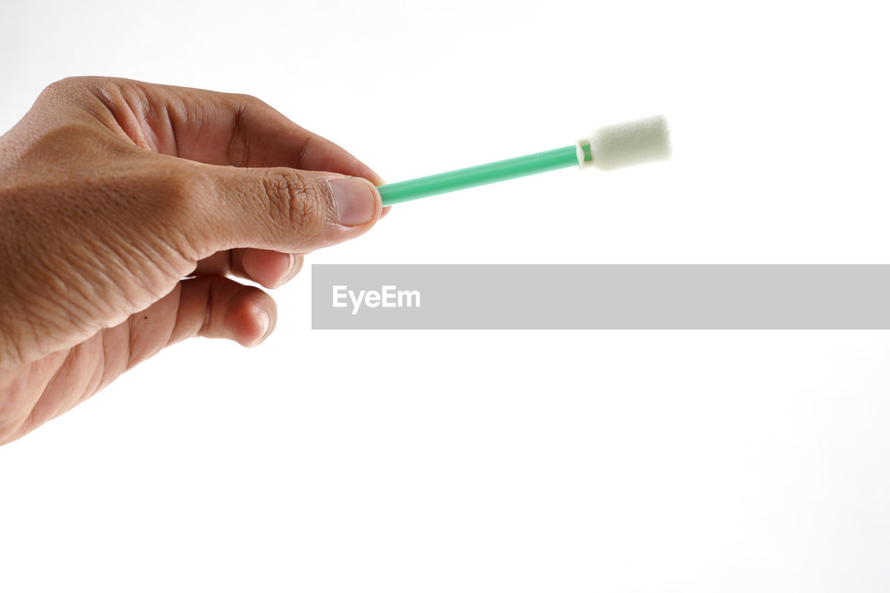 Close-up of hand holding cleaning equipment against white background