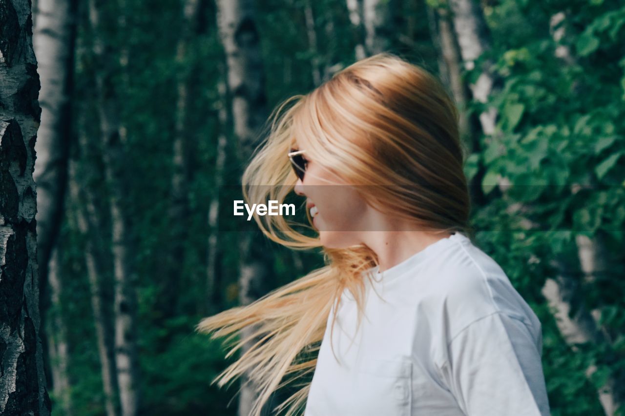 Young woman standing against trees