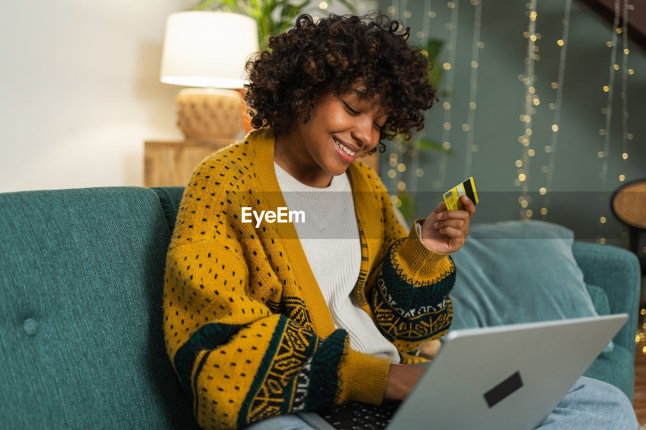 young woman using digital tablet while sitting on sofa at home