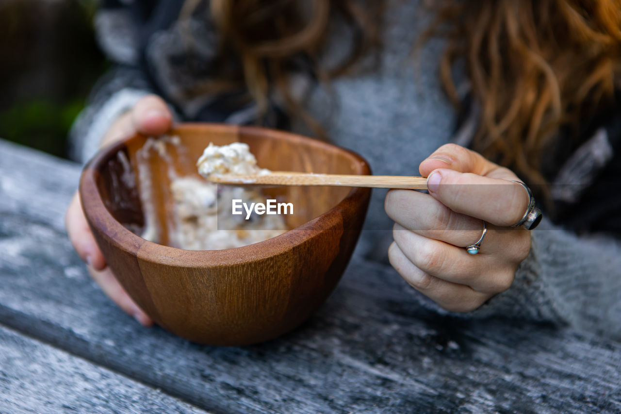 Midsection of woman eating ice cream in bowl