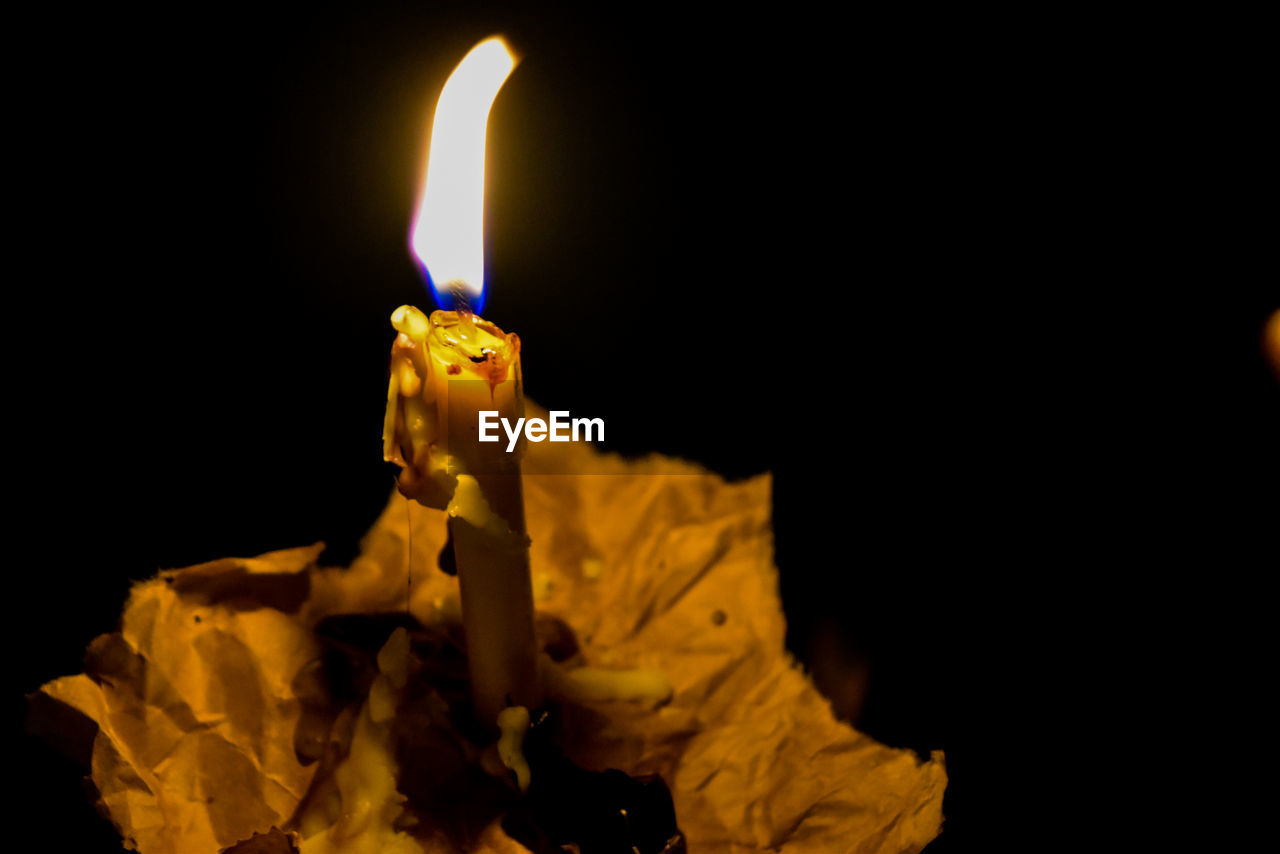 Close-up of illuminated candle in darkroom