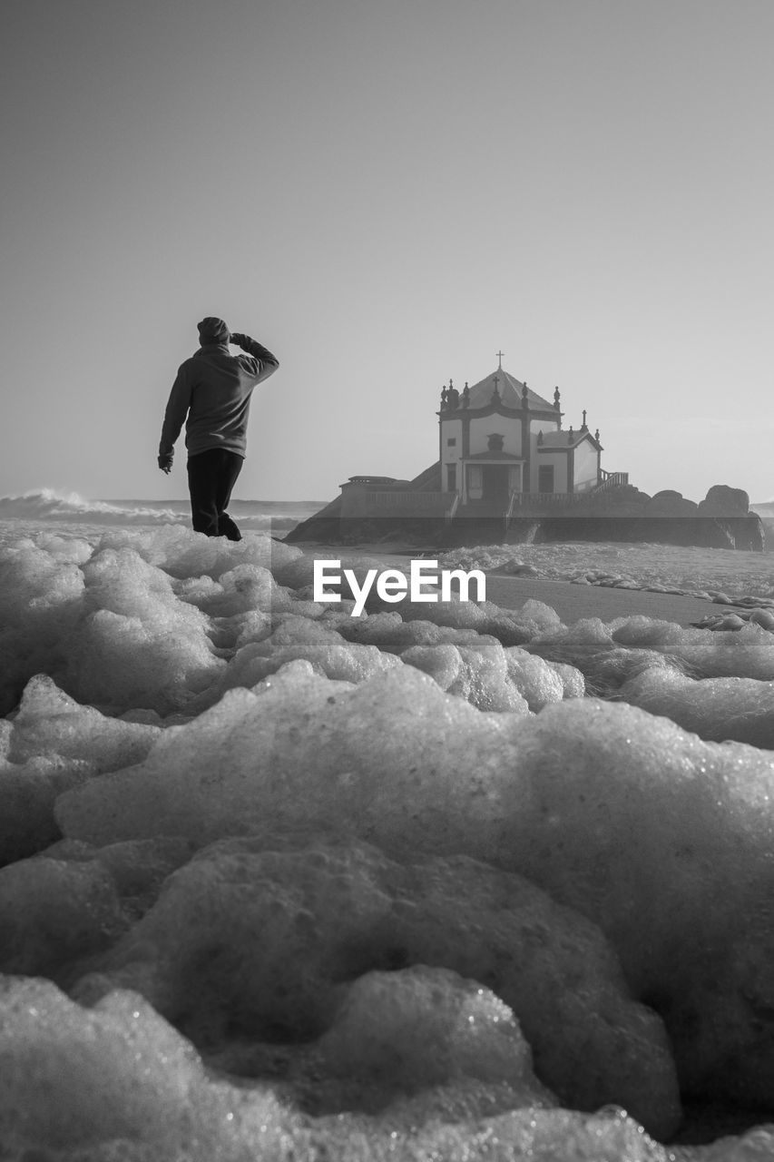 Rear view of man standing in front of church at beach