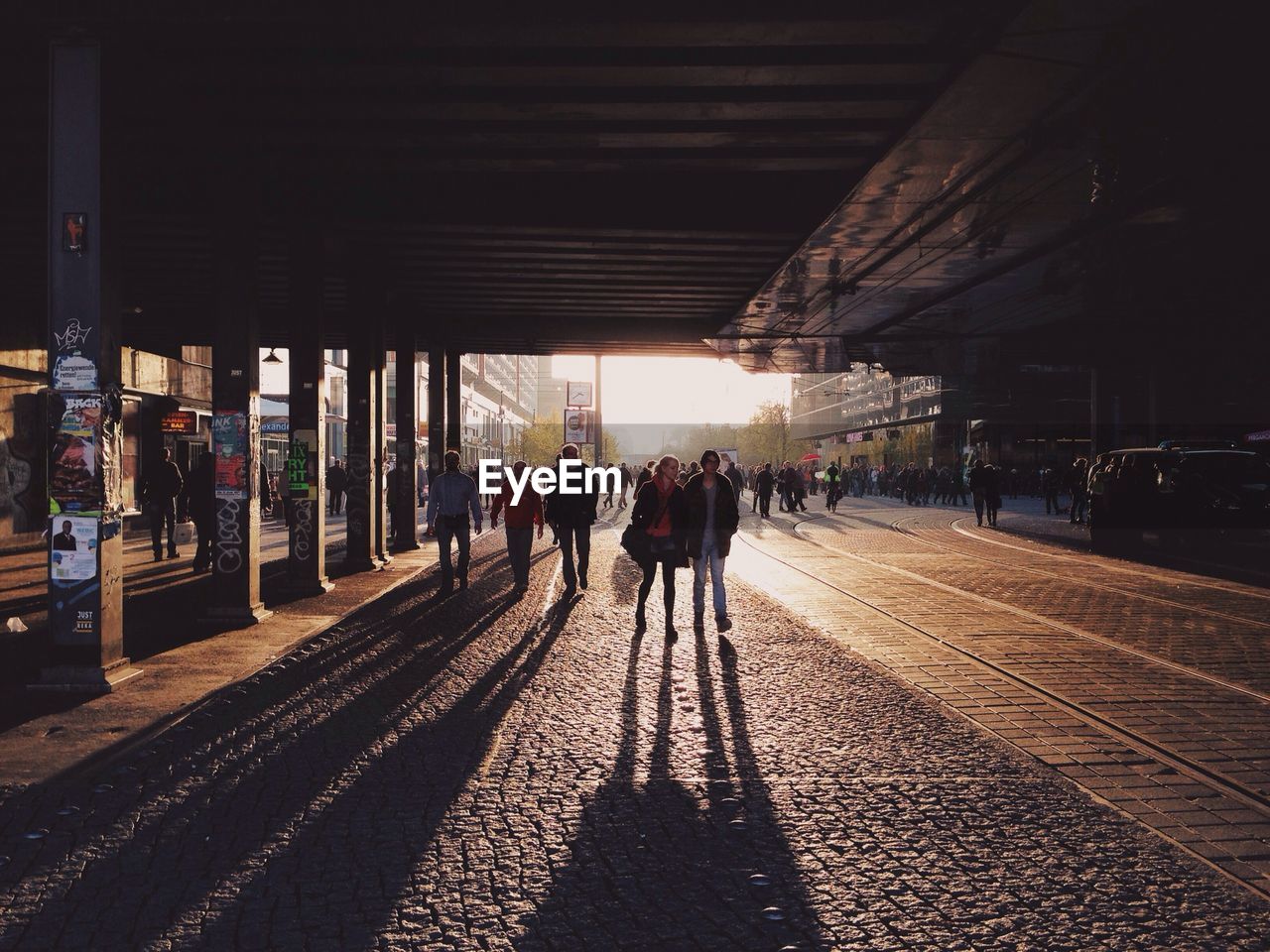 People walking under bridge on street