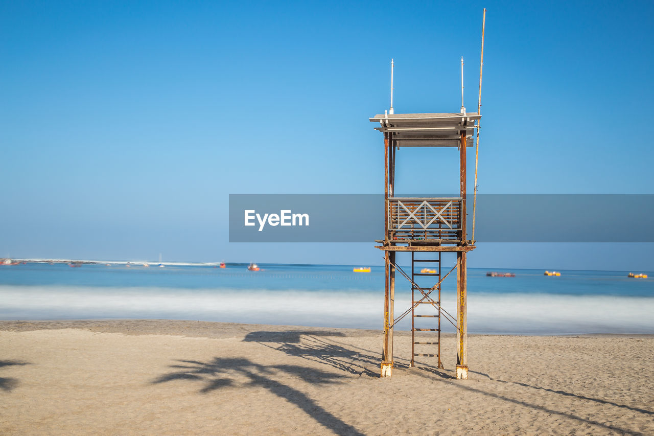 Lookout tower at beach against clear blue sky