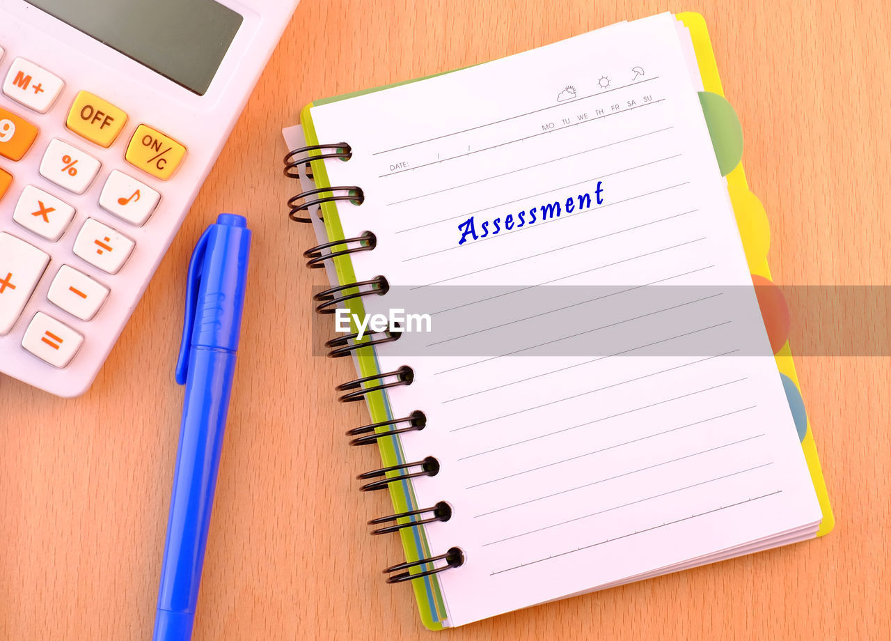 High angle view of pen and book with calculator on table