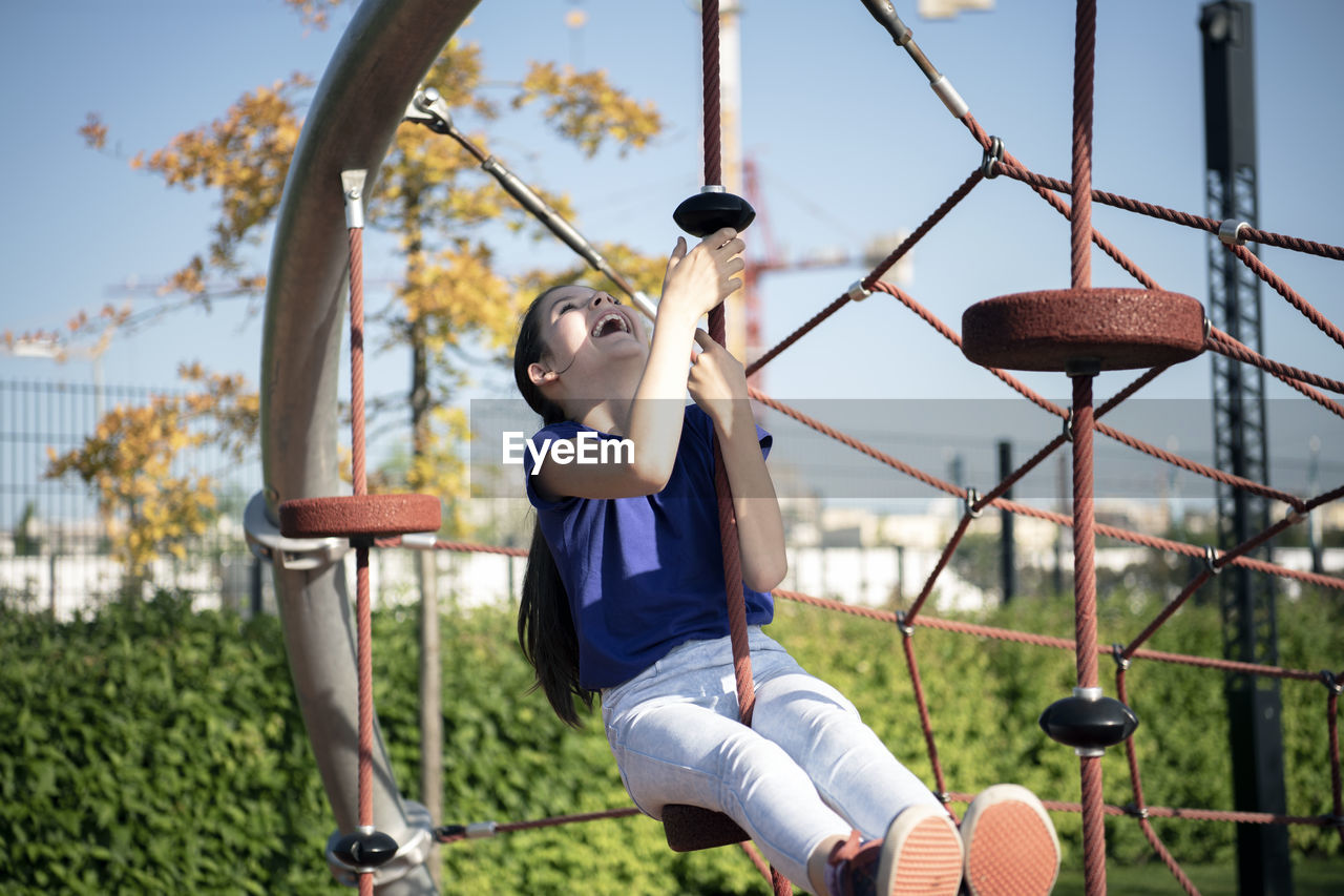 Happy girl sitting on outdoor play equipment