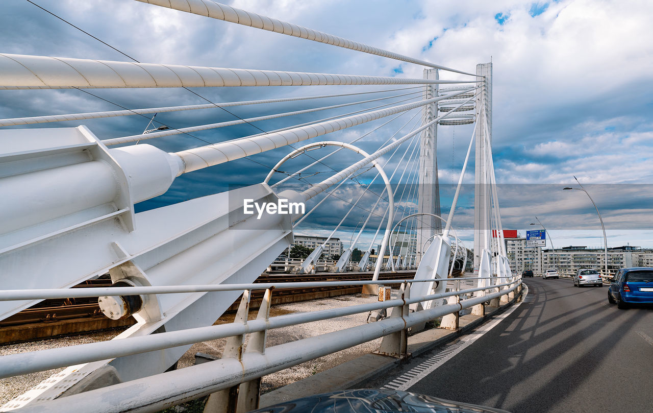 White cable bridge over river in city against sky