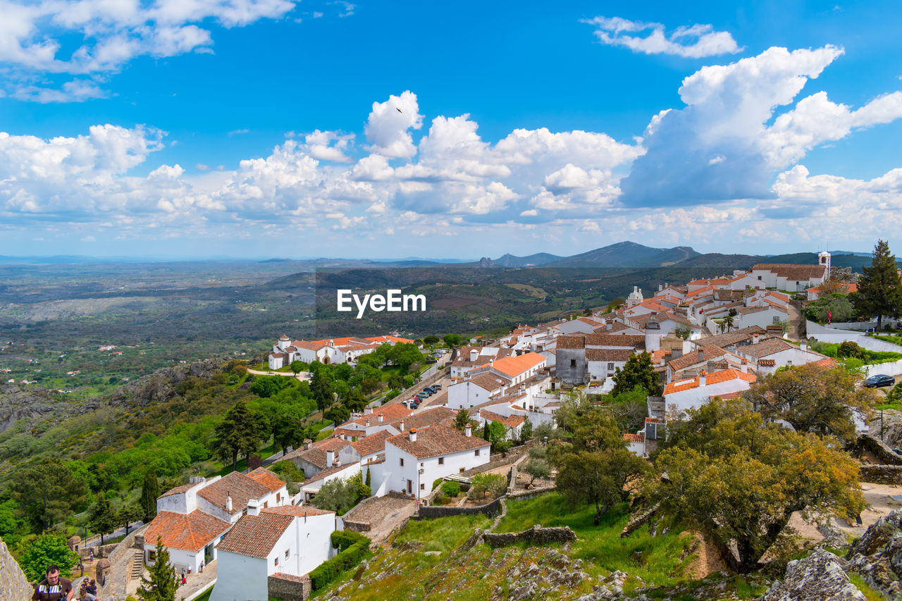 HIGH ANGLE VIEW OF TOWNSCAPE BY TREES AGAINST SKY