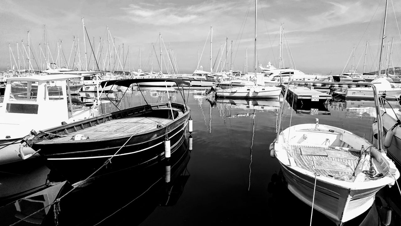 Boats moored at harbor against sky