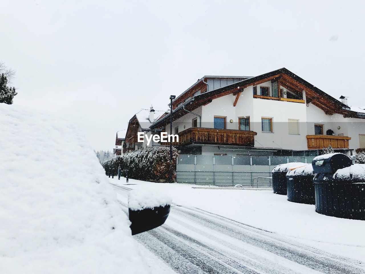 SNOW COVERED HOUSE BY BUILDINGS AGAINST SKY