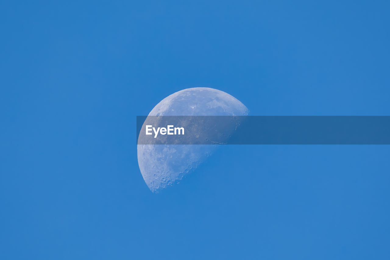 LOW ANGLE VIEW OF MOON AGAINST BLUE SKY