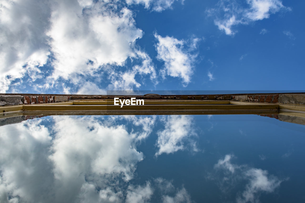 LOW ANGLE VIEW OF BRIDGE OVER RIVER AGAINST CLOUDY SKY