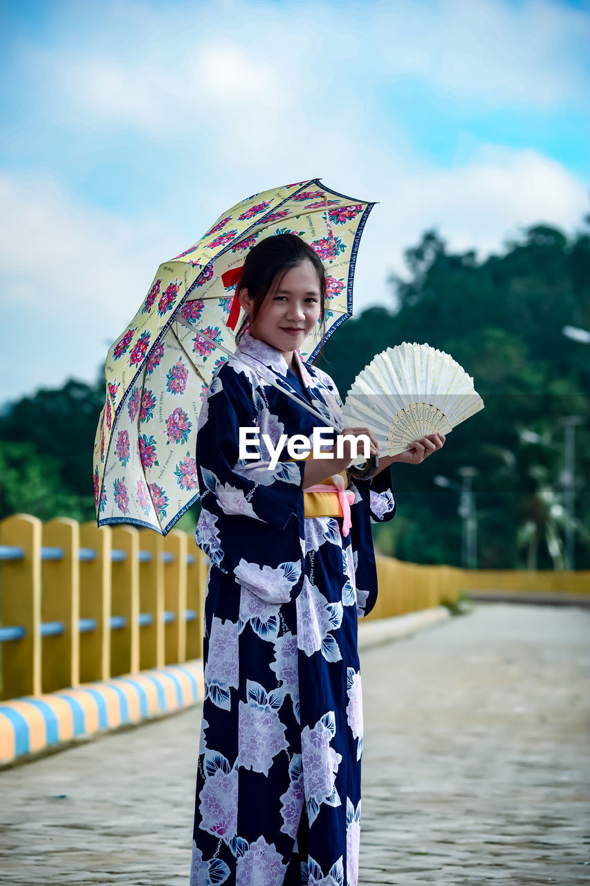 Full length of woman with umbrella standing in rain