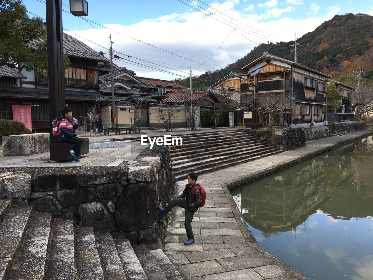 REAR VIEW OF WOMAN WALKING ON FOOTPATH BY WATER