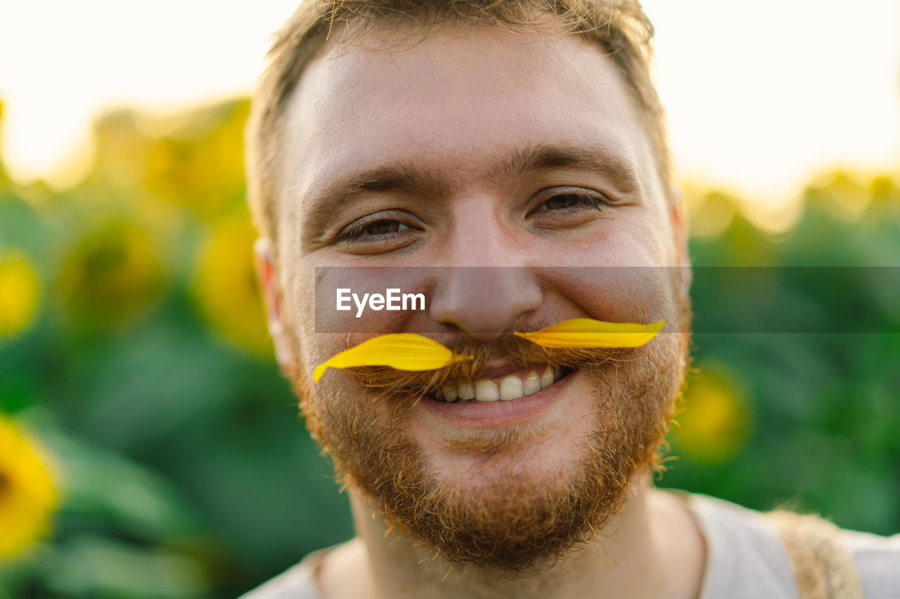 Man with yellow flowers in mustache. breathe free. a man has fun in nature.