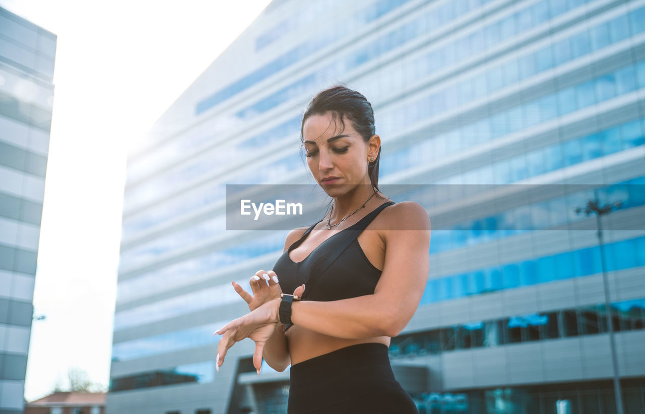 LOW ANGLE VIEW OF WOMAN STANDING ON CITY