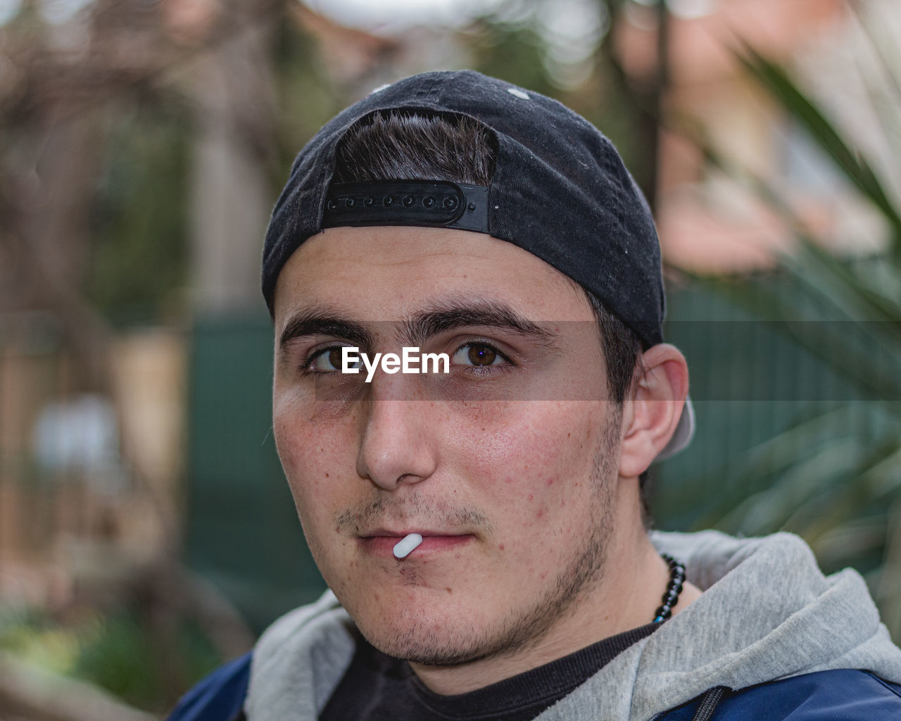 PORTRAIT OF YOUNG MAN WEARING HAT OUTDOORS