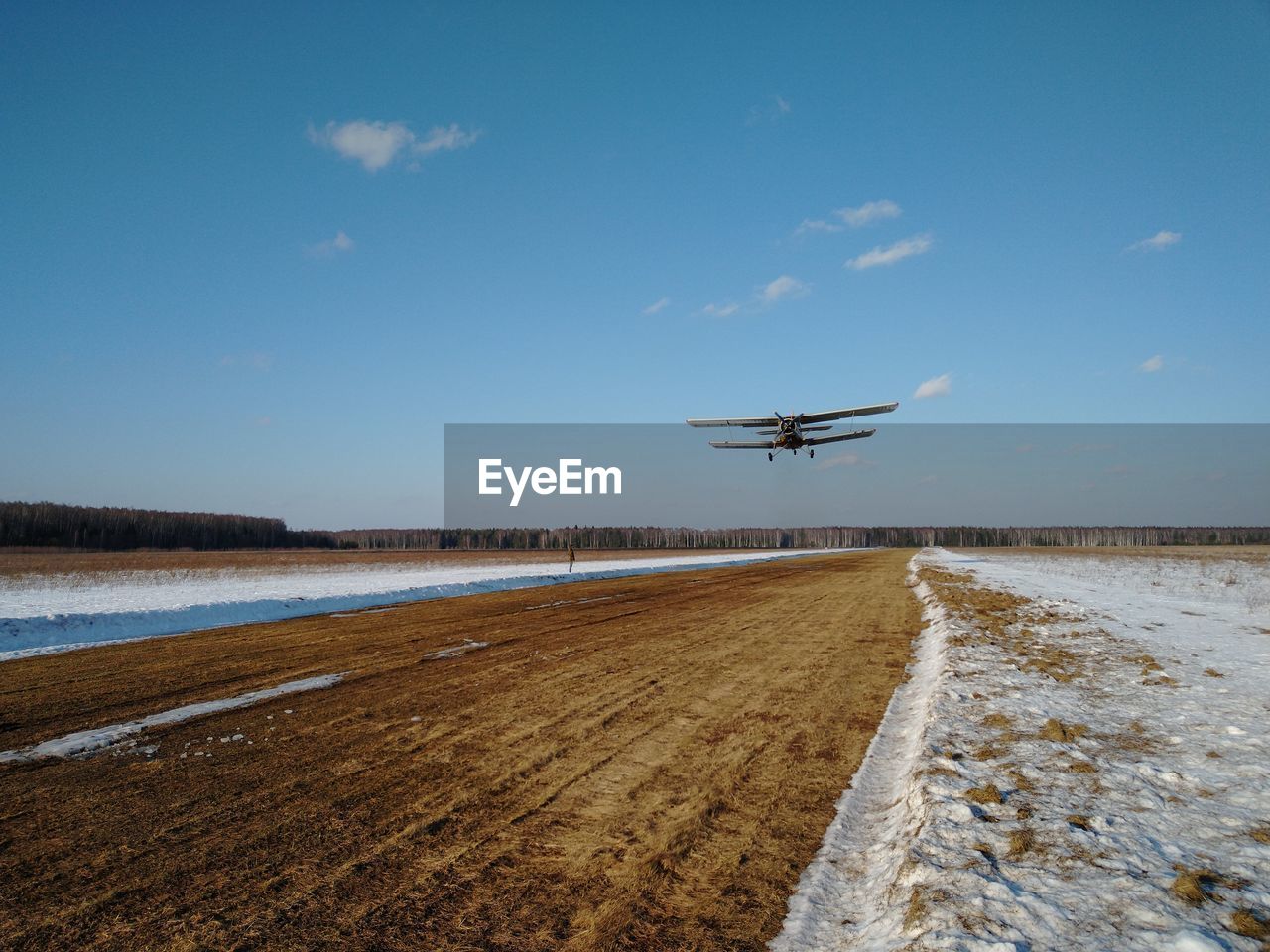 AIRPLANE FLYING OVER LANDSCAPE AGAINST SKY