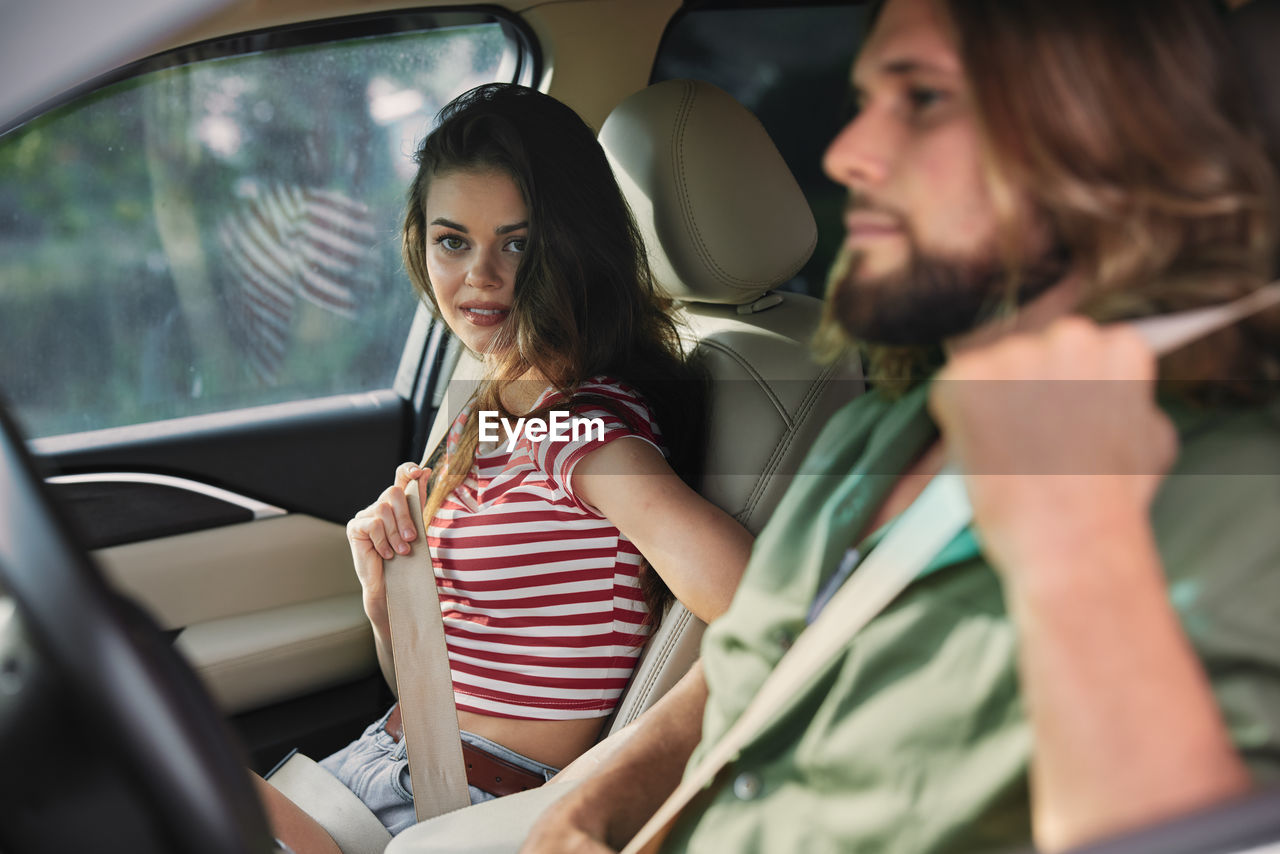 side view of woman using mobile phone while sitting in car