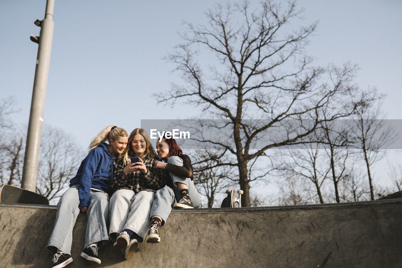 Teenage girls using phone in skatepark