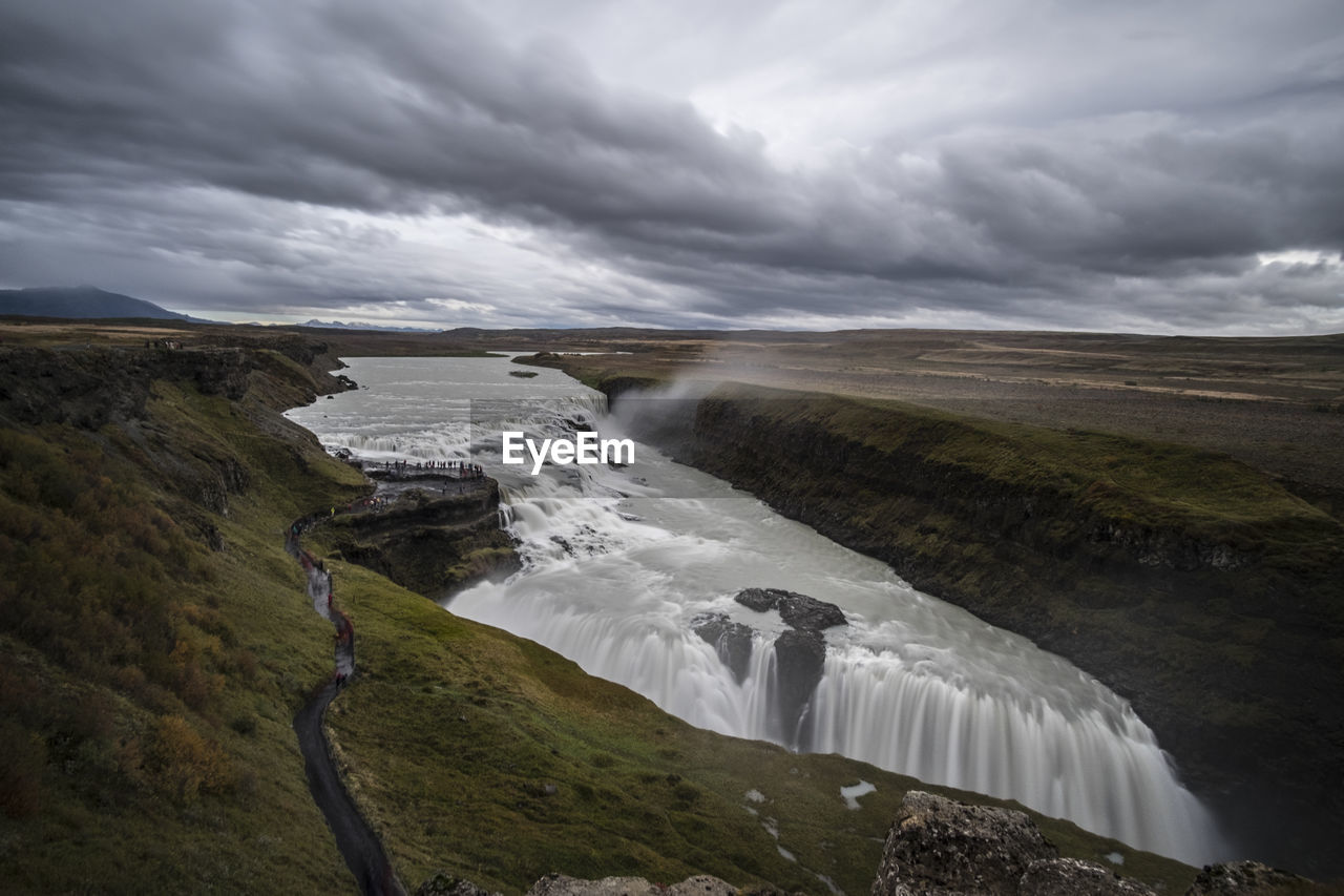 SCENIC VIEW OF WATERFALL AMIDST LANDSCAPE AGAINST SKY