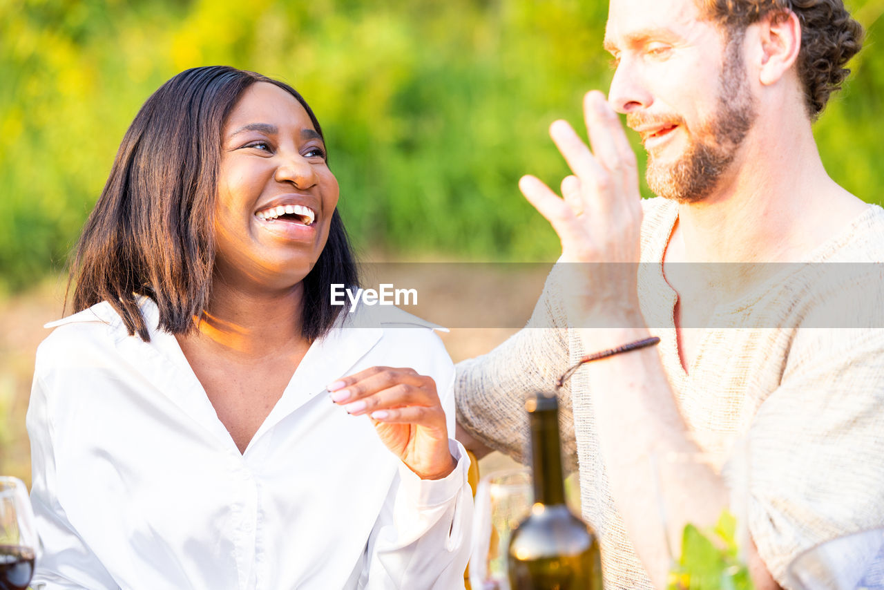 Joyful duo mixed race couple laughs amidst garden party festivities