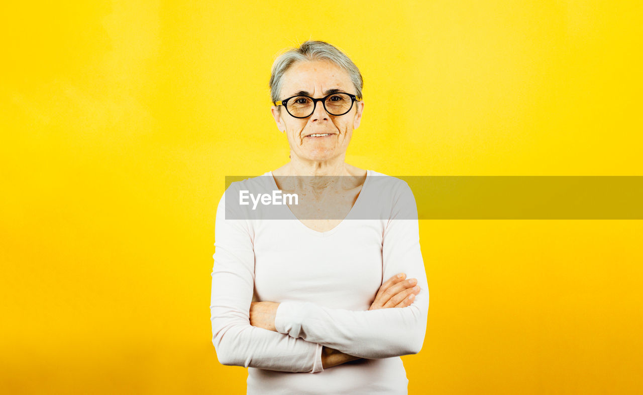 portrait of young man standing against yellow background