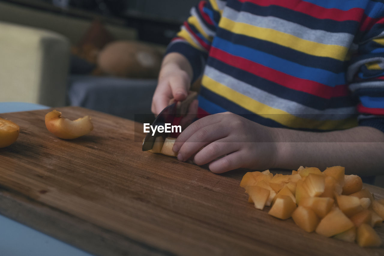 MIDSECTION OF MAN PREPARING FOOD AT TABLE