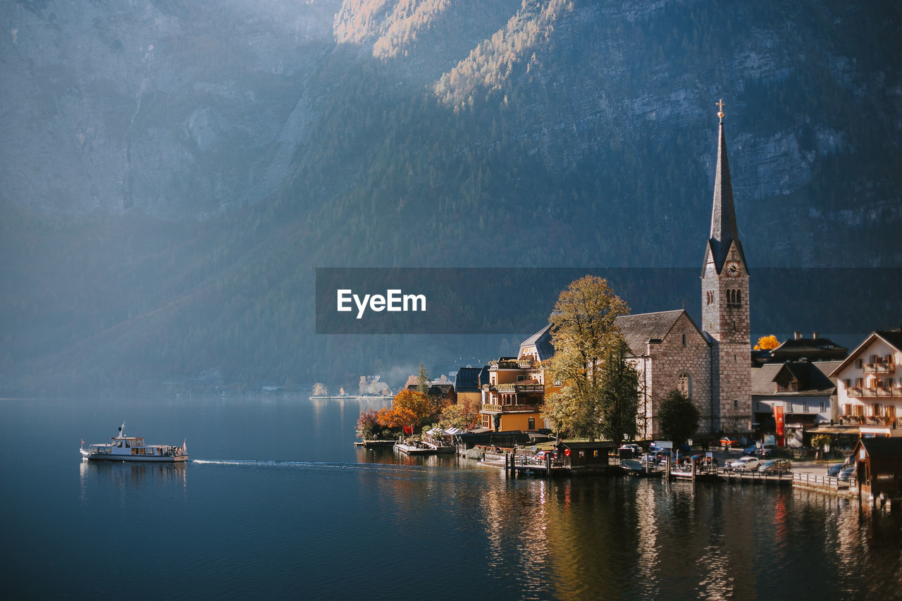 Panoramic view of lake by buildings against mountains