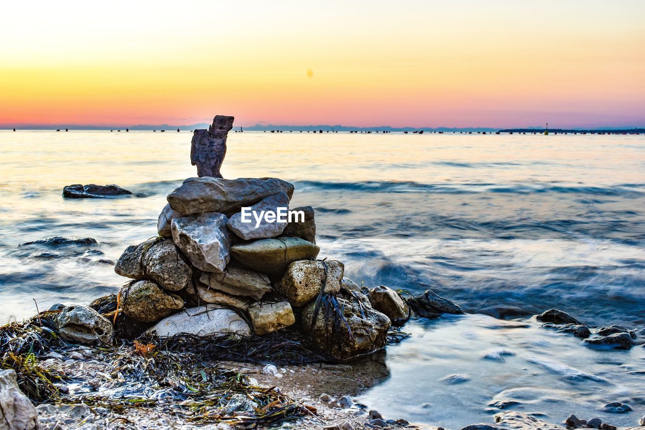 SCENIC VIEW OF ROCKS AT BEACH DURING SUNSET