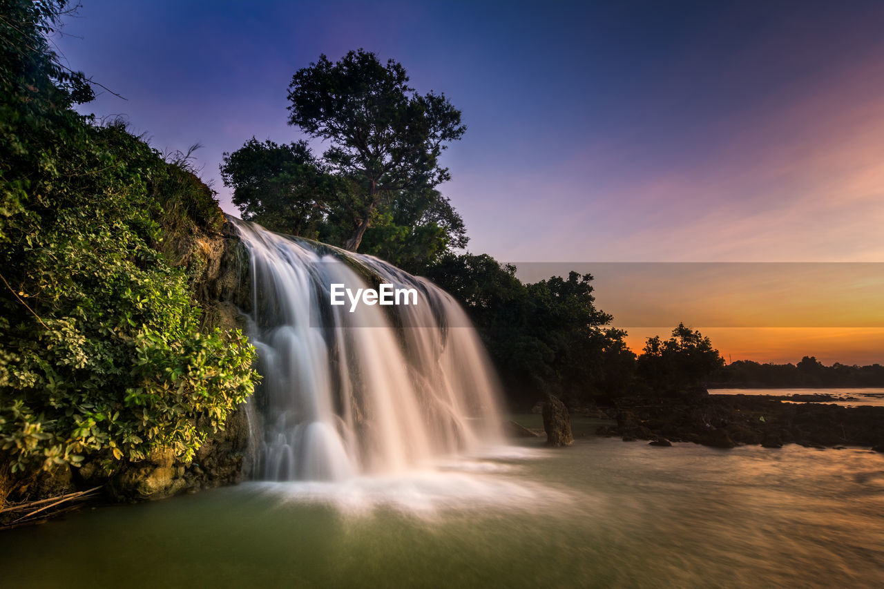 Scenic view of waterfall against sky during sunset