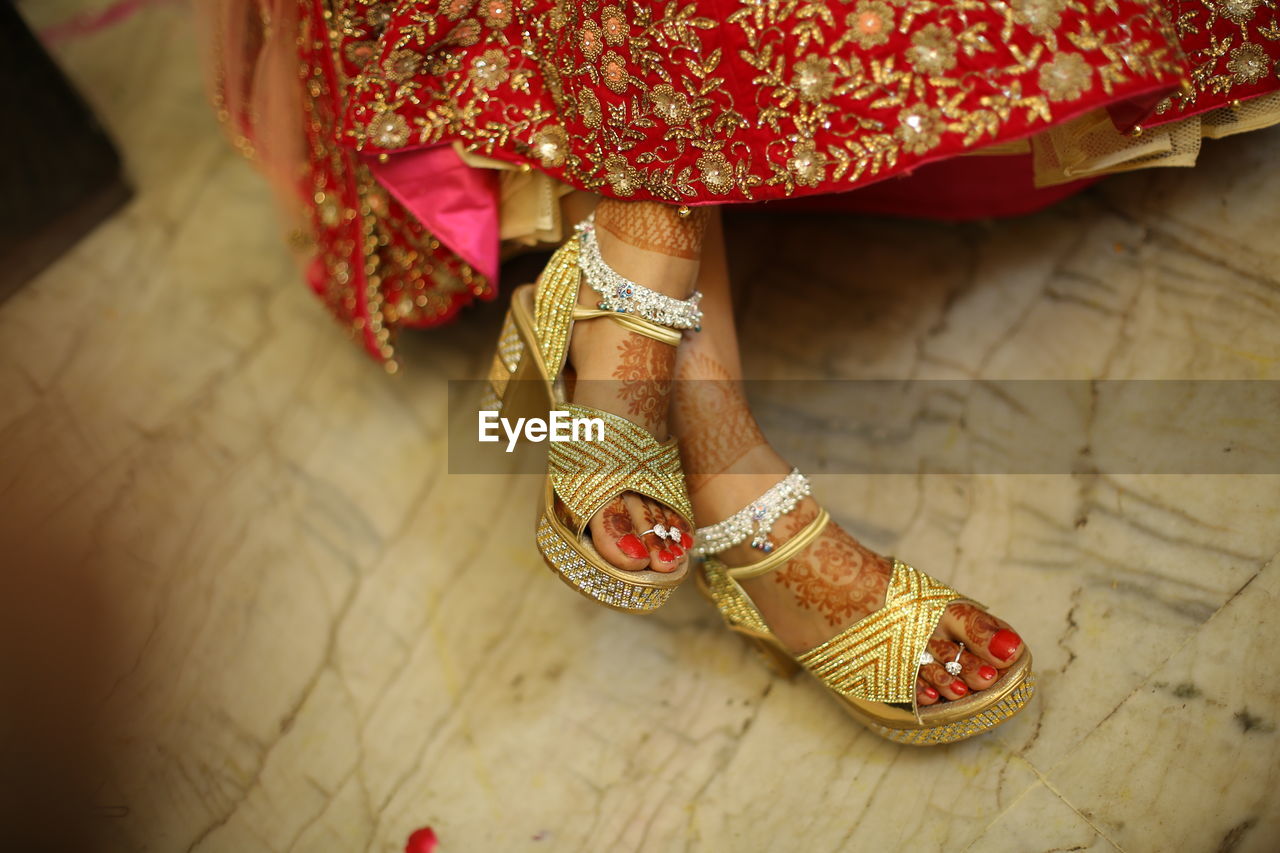 Low section of woman wearing red shoes on floor