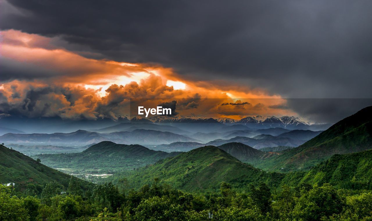 Scenic view of clouds over mountains during sunset