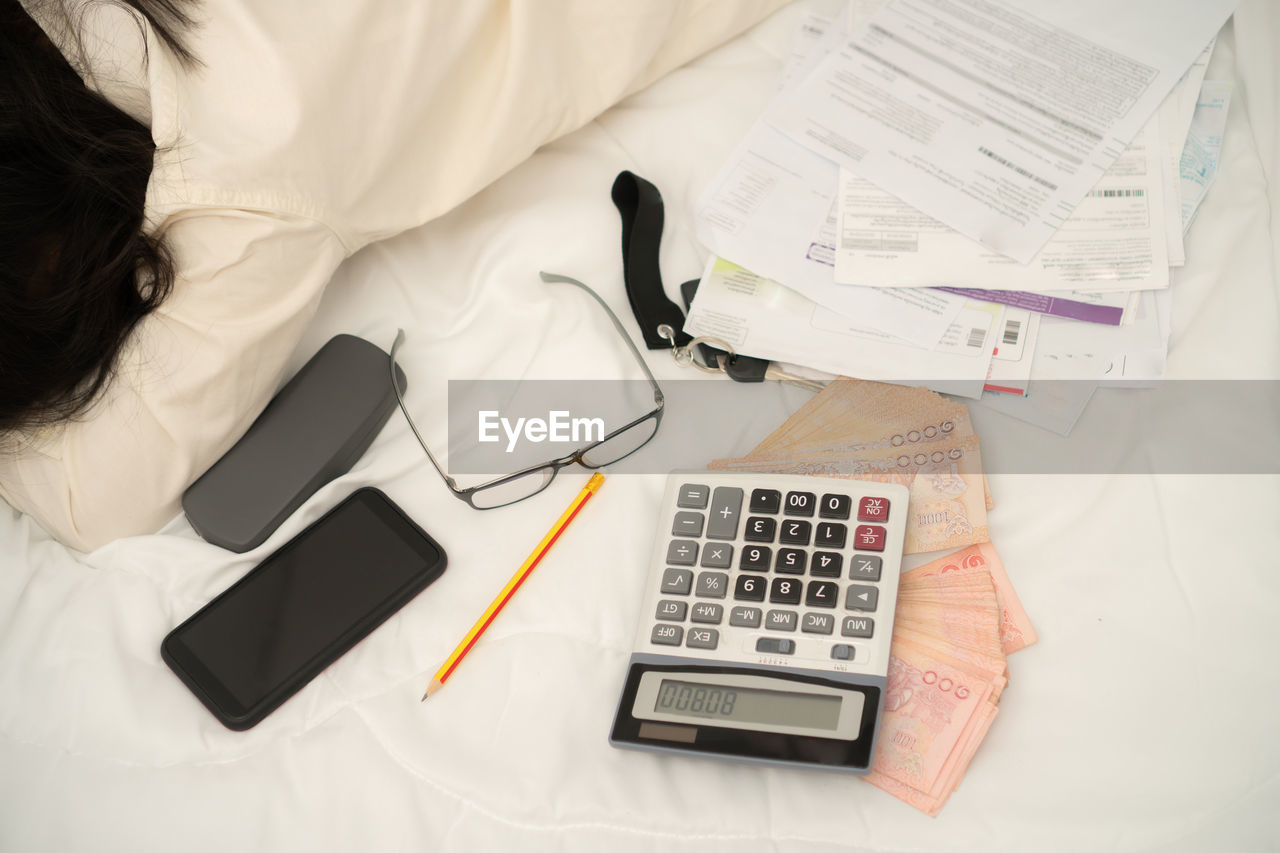 High angle view of paper and currency by equipment on table